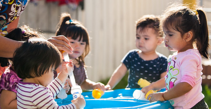 Group of kids playing around a water table